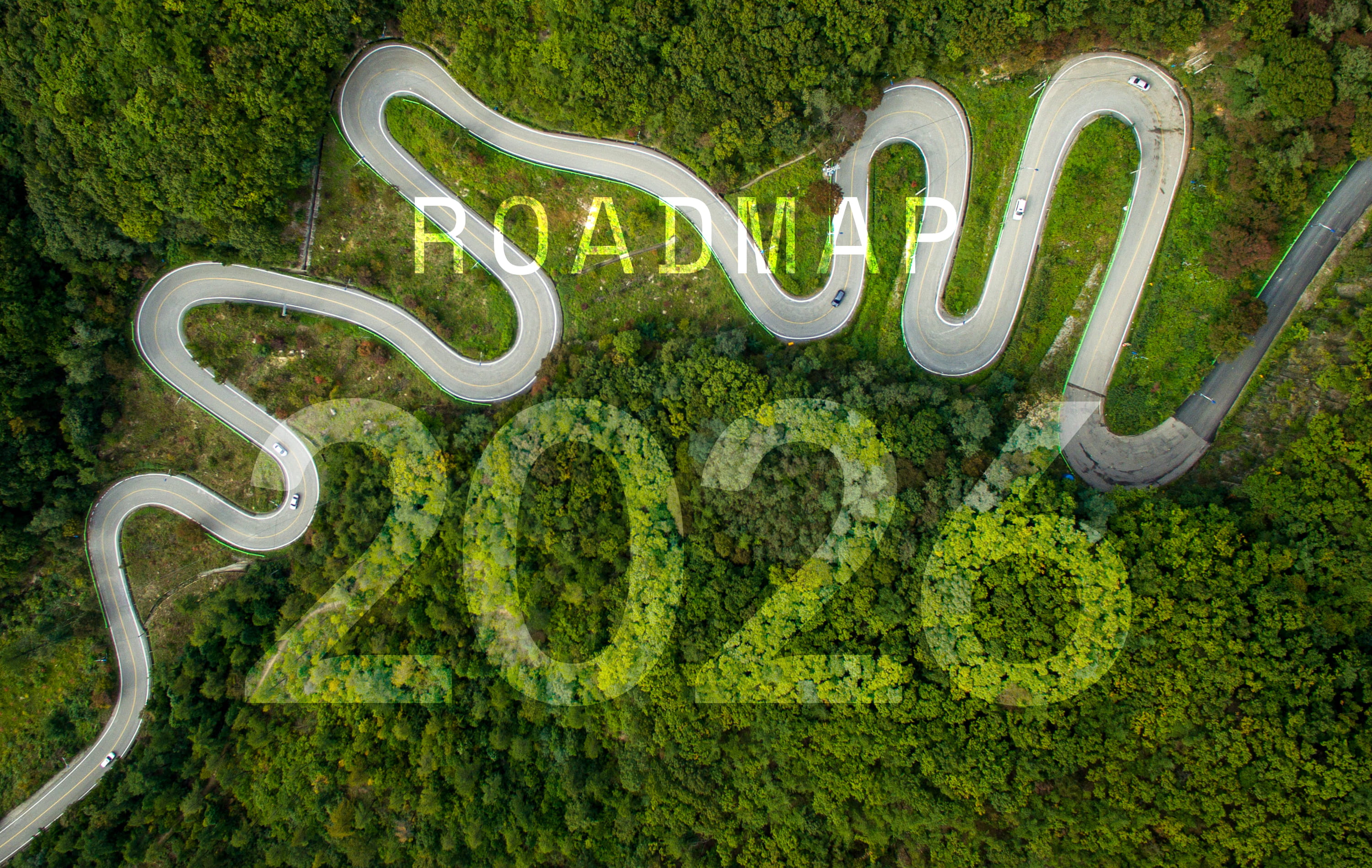 Eine Vogelperspektive auf eine kurvenreiche Straße durch einen grünen Wald, wobei die Jahreszahl 2026 transparent eingeblendet ist. 